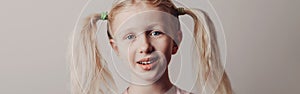 Closeup portrait of surprised sad Caucasian girl on light background. Child with long pig tails hair posing looking in camera. Kid