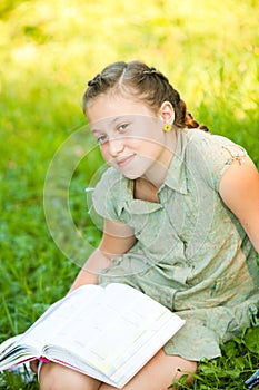 Closeup portrait of teen girl on a grass with book