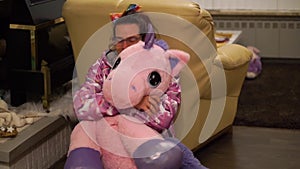 Closeup portrait of a transgender lady cuddling with a stuffed pink unicorn, LGBT diversity cute and funny, person with autism and