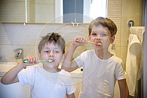 Closeup portrait of twins kids toddler boy sibling in bathroom toilet washing face hands brushing teeth with toothbrush playing