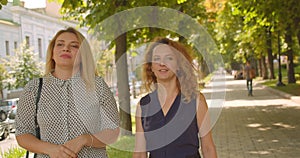 Closeup portrait of two female friends walking having conversation smiling happily in park outdoors