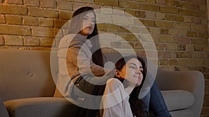 Closeup portrait of two young pretty women watching a movie TV sitting laidback on the floor in a cozy apartment indoors