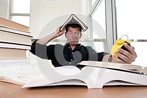 Closeup portrait of white man surrounded by tons of books, alarm clock, stressed from project deadline, study, exams