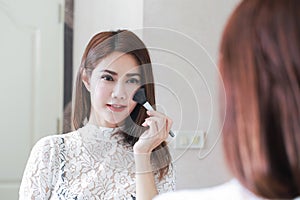 Closeup portrait of woman with makeup brush near face.