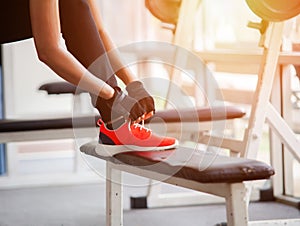 Closeup portrait of a woman tying shoelaces. Beautiful woman tying shoelaces at gym .  Woman runner tying laces before training