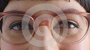 Closeup portrait of a woman wearing glasses and looking at the camera. Face of a female with brown eyes and winged