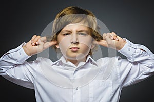 Closeup portrait of worried boy covering her ears, observing. Hear nothing. Human emotions, facial expressions