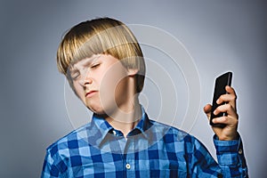 Closeup Portrait of worried stressed boy with mobile going irritation on gray background