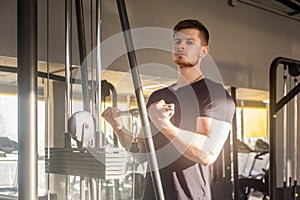 Closeup portrait of young adult sport athlete man training at gym alone, standing and lifting weights in the gym, doing exercises