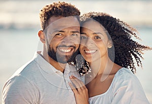 Closeup portrait of an young affectionate mixed race couple standing on the beach and smiling during sunset outdoors