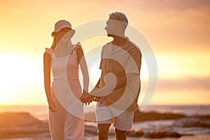 Closeup portrait of an young affectionate mixed race couple standing on the beach and smiling during sunset outdoors