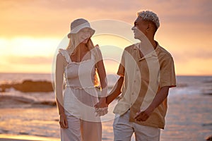 Closeup portrait of an young affectionate mixed race couple standing on the beach and smiling during sunset outdoors