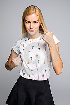 Closeup portrait of young angry annoyed woman with bad attitude giving talk to hand gesture showing fist. isolated grey wall backg
