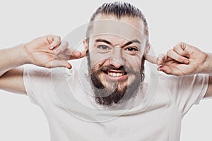 Closeup portrait young, angry, unhappy, stressed man covering his ears isolated on white background.