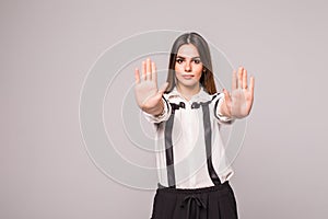 Closeup portrait young annoyed angry woman with bad attitude giving talk to hand gesture with palm outward isolated grey wall back