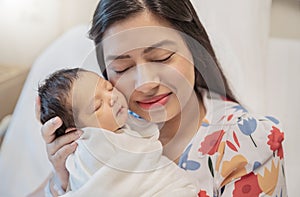 Closeup portrait of young asian Indian mother holding newborn baby with copy space.