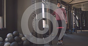 Closeup portrait of young attractive athletic muslim female in hijab doing resistance training in gym indoors