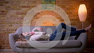 Closeup portrait of young attractive caucasian brunette female having a phone call lying laidback on the couch indoors