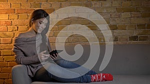 Closeup portrait of young attractive caucasian female using the tablet while resting laidback on the couch and smiling photo