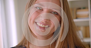 Closeup portrait of young attractive caucasian girl looking at camera laughing happily in apartment indoors