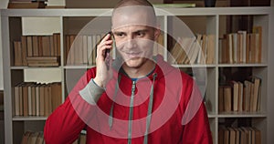 Closeup portrait of young attractive caucasian male student having a phone call in the college library indoors