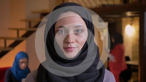 Closeup portrait of young beautiful arabian female office worker in black hijab looking straight at camera and smiling