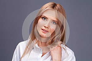 Closeup portrait of a young beautiful blonde woman in a white shirt