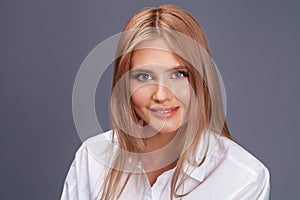 Closeup portrait of a young beautiful blonde woman in a white shirt