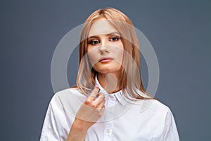 Closeup portrait of a young beautiful blonde woman in a white shirt