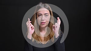 Closeup portrait of young beautiful caucasian female being anxious and having her fingers crossed in hope looking at