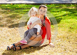 Closeup portrait of a young beautiful mother with little curly daughter in autumn park