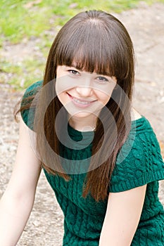 Closeup portrait of young beautiful woman brunette girl sitting outdoors happy smiling & looking at camera