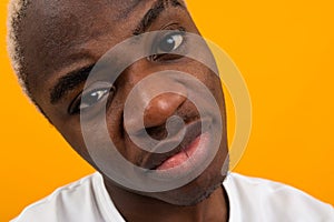 Closeup portrait young black african man in white t-shirt posing on yellow isolated background