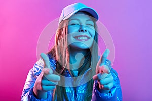 Closeup portrait of young brunette female pointing at camera with both hands, looking with happy toothy smile, satisfied teenager