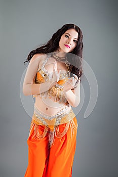 Closeup portrait of young brunette lady poses in orange belly dancer costume
