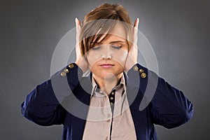 Closeup portrait of a young businesswoman covering ears with her