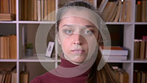 Closeup portrait of young caucasian female student looking at camera in the unversity library indoors