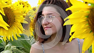 Closeup portrait of young caucasian woman in glasses looking up. Beautiful girl posing in sunflowers field