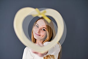 Closeup portrait of young female holding heart shape isolated on gray background