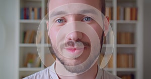 Closeup portrait of young handsome caucasian male student looking at camera smiling cheerfully in the college library