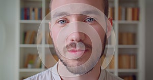 Closeup portrait of young handsome caucasian male student looking at camera smiling happily in the college library with