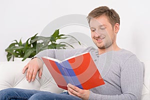 Closeup portrait of young, handsome man reading book.