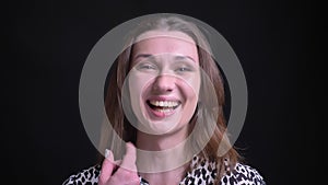 Closeup portrait of young happy caucasian brunette female smiling and laughing cheerfully while looking straight at