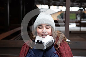 Closeup portrait of a young happy woman enjoying winter wearing scarf and knitted hat