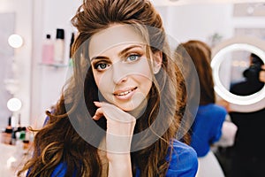 Closeup portrait young joyful woman in blue shirt with long brunette hair expressing positive emotions to camera in