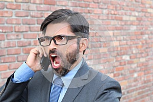 Closeup portrait, young man annoyed, frustrated, off by someone talking on his mobile phone, bad news, isolated outdoors