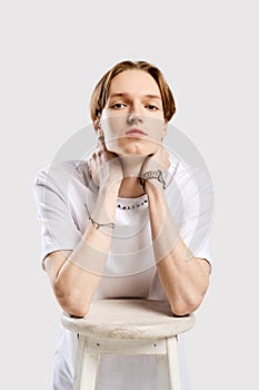 Closeup portrait of young man in white t-shirt leaning to a sit of a chair