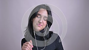 Closeup portrait of young pretty caucasian female in vibes dancing and listening to music in front of the camera