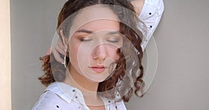 Closeup portrait of young pretty long haired curly caucasian female model posing in front of the camera with background