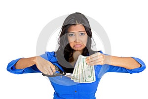 Closeup portrait of a young sa business woman cutting budget, trimming dollar bills cash money with scissors